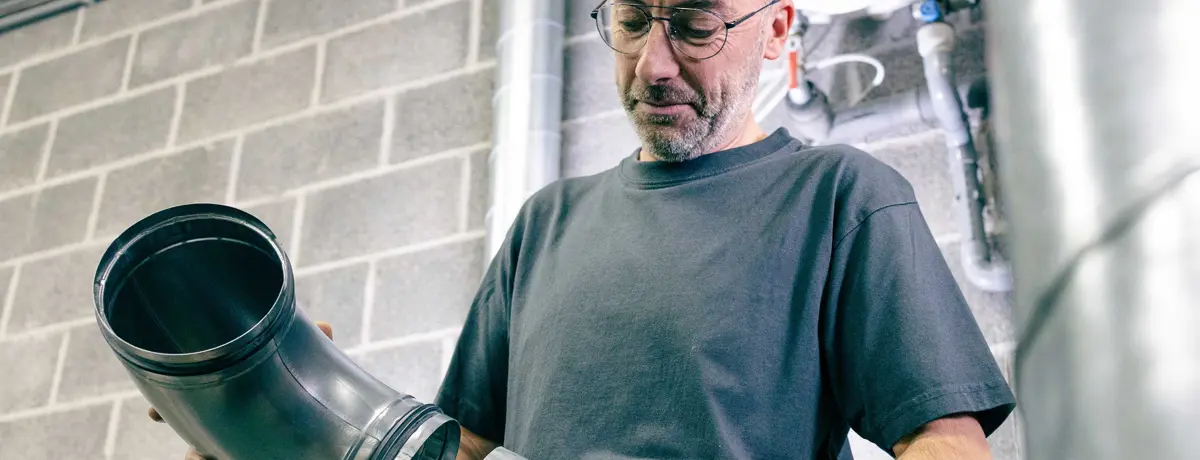 Spécialiste analysant un conduit de ventilation pour une solution innovante dans le bâtiment.