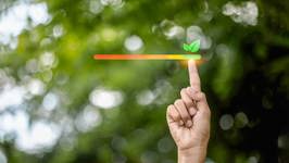 Hand die een schaal voor duurzaamheid en energie-efficiëntie aanwijst, met een blad als symbool voor een milieuvriendelijke keuze.