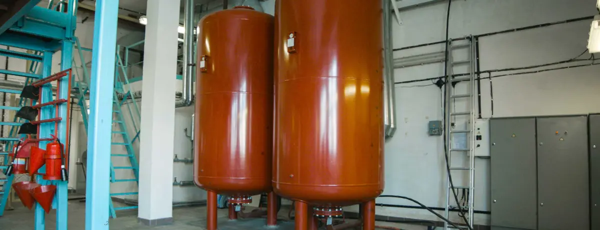 NL: Twee verticale opslagtanks in een technische ruimte. FR: Deux cuves de stockage verticales dans un local technique.